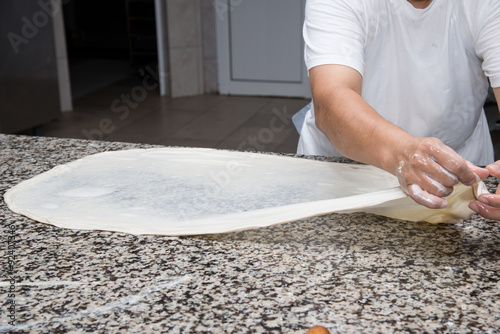 close up of female hands kneading dough and making banitsa