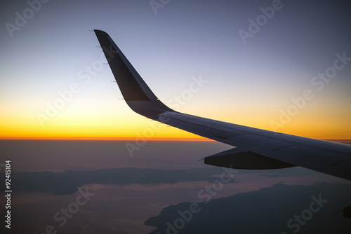 Wing of an airplane at sunset, view from window.