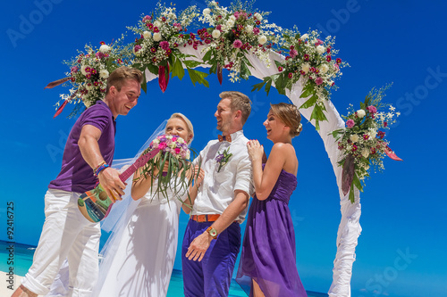 bride, groom and guests enjoying beach wedding in tropics, on we