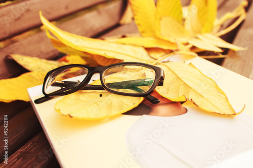 glasses with a magazine on a bench in autumn park 