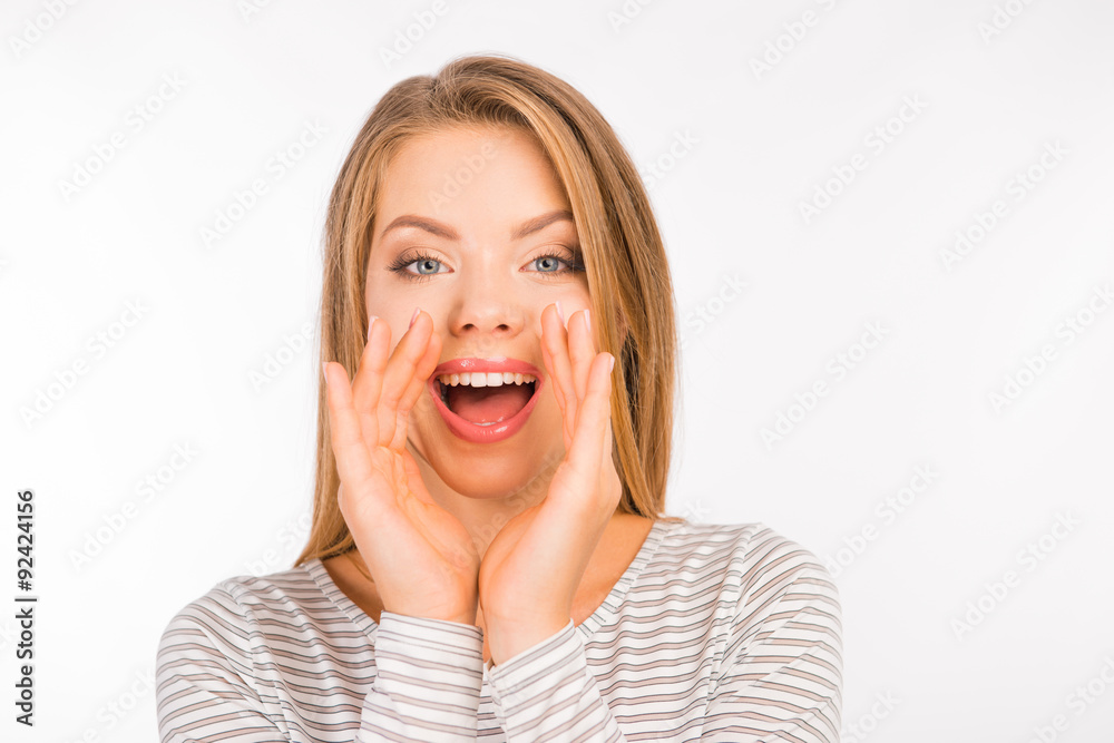 Pretty young woman talking holding hands near mouth Pretty young woman talking holding hands near mouth