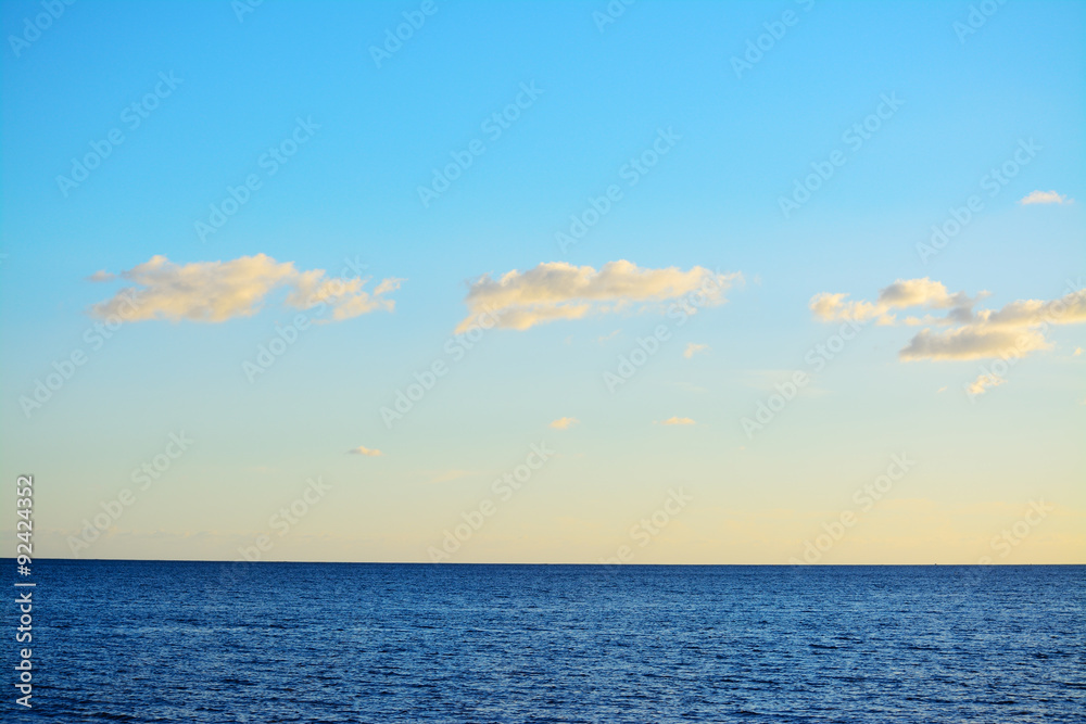 blue sea under a clear sky with small clouds