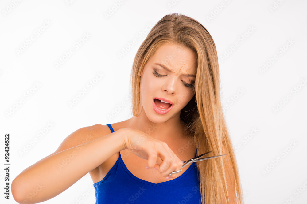 Upset woman cutting her split ends Upset woman cutting her split ends