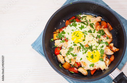 fried eggs with chicken breast, pepper and cheese in a frying pan