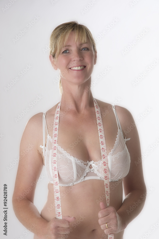 Mature woman holding a tape measure over her bra Stock Photo