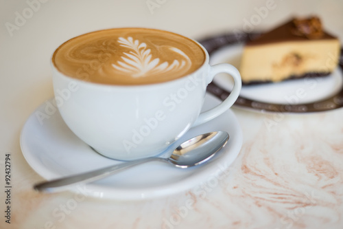 Cappuchino or latte coffe in a white cup on with a cake