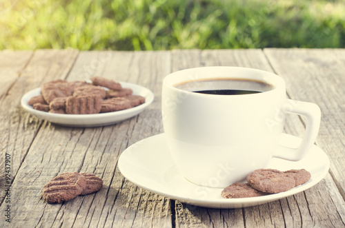 Cup of coffee with cookies on a wooden table with natural background