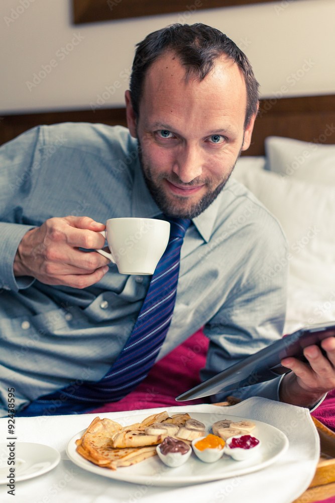 Businessman working on tablet pc during breakfast at home/hotel. Businessman working on tablet pc during breakfast at home/hotel.