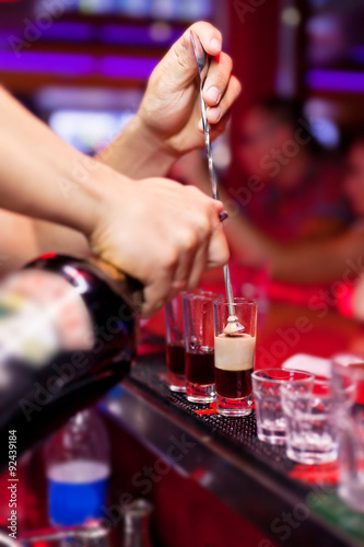 Barman's hands in interior bar are poured liquor