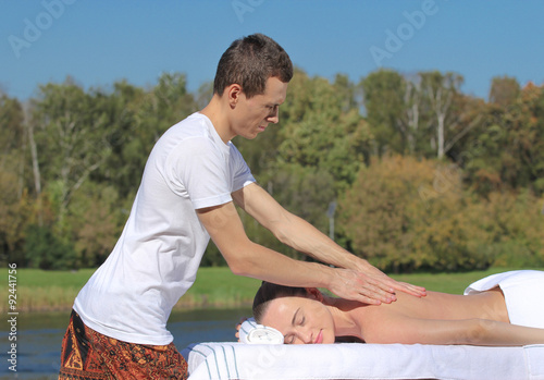 Man giving massage to young brunette outdoors