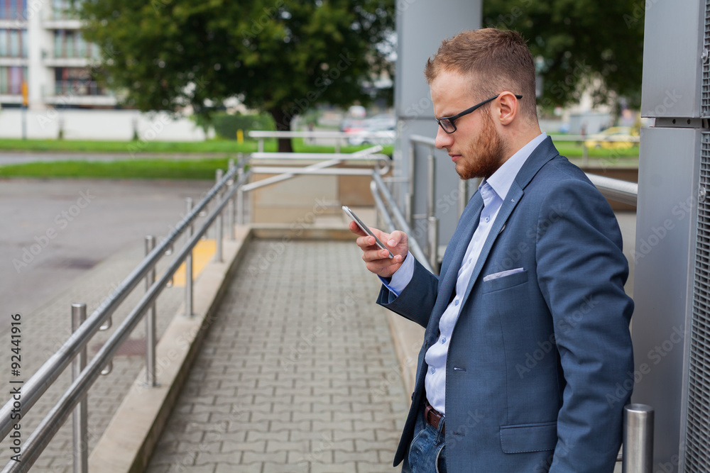 Caucasian businessman outside office using mobile phone outside office building. Caucasian businessman outside office using mobile phone outside office building.