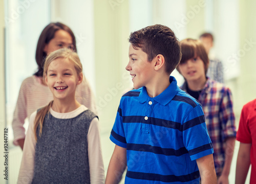 group of smiling school kids walking in corridor
