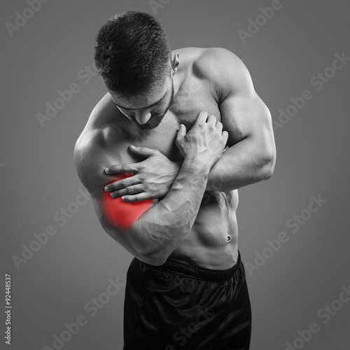 Foto Muscular shirtless man with biceps pain over gray background