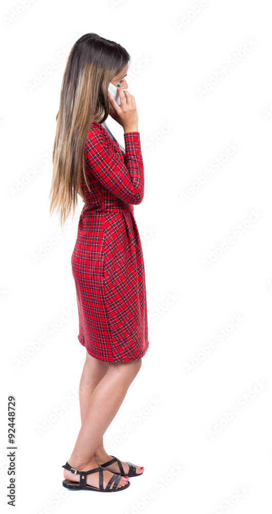 Fototapeta premium back view of standing young beautiful woman and using a mobile