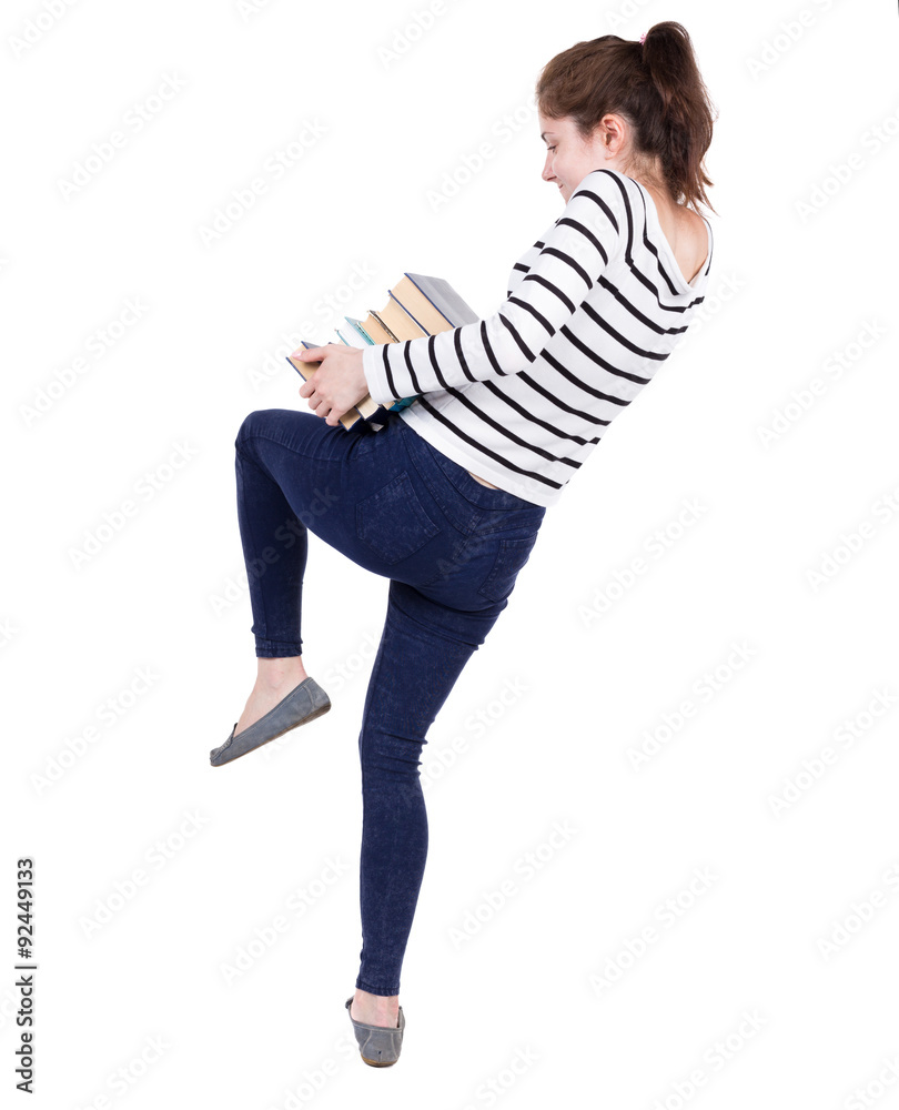 A girl carries a heavy pile of books. A girl carries a heavy pile of books.
