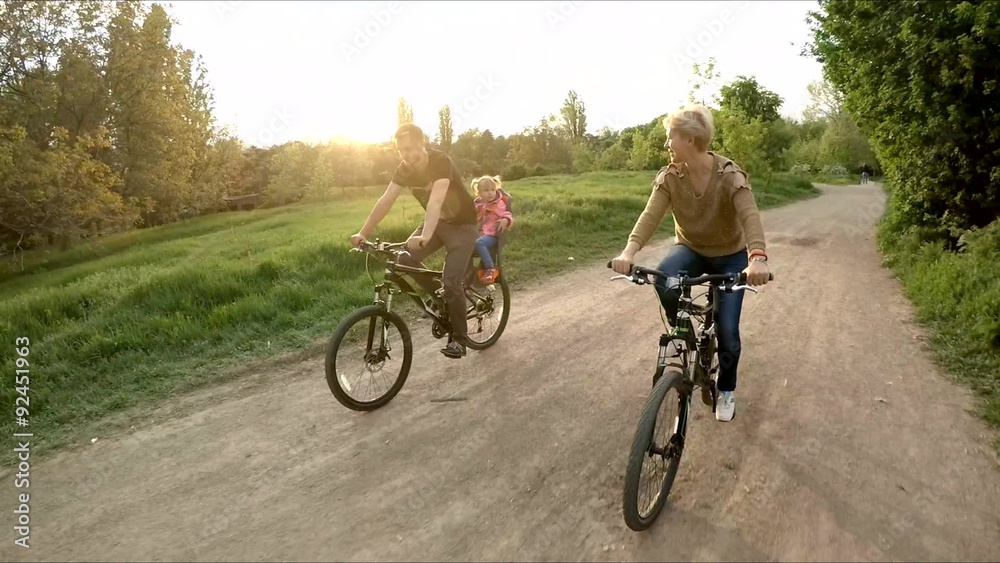 Young Happy Family Riding Bicycles In Green Park Young Happy Family Riding Bicycles In Green Park
