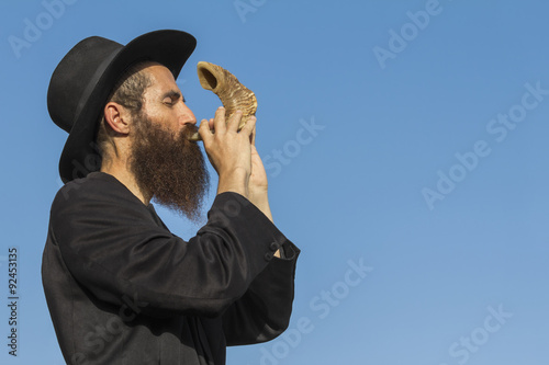 Photography Orthodox Jewish man blast in Shofar at Rosh Hashana holiday on blue sky backgrou