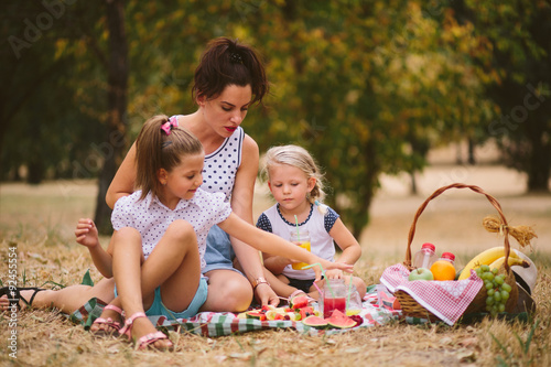 Mmother and two daughters on a picnic in the park photo