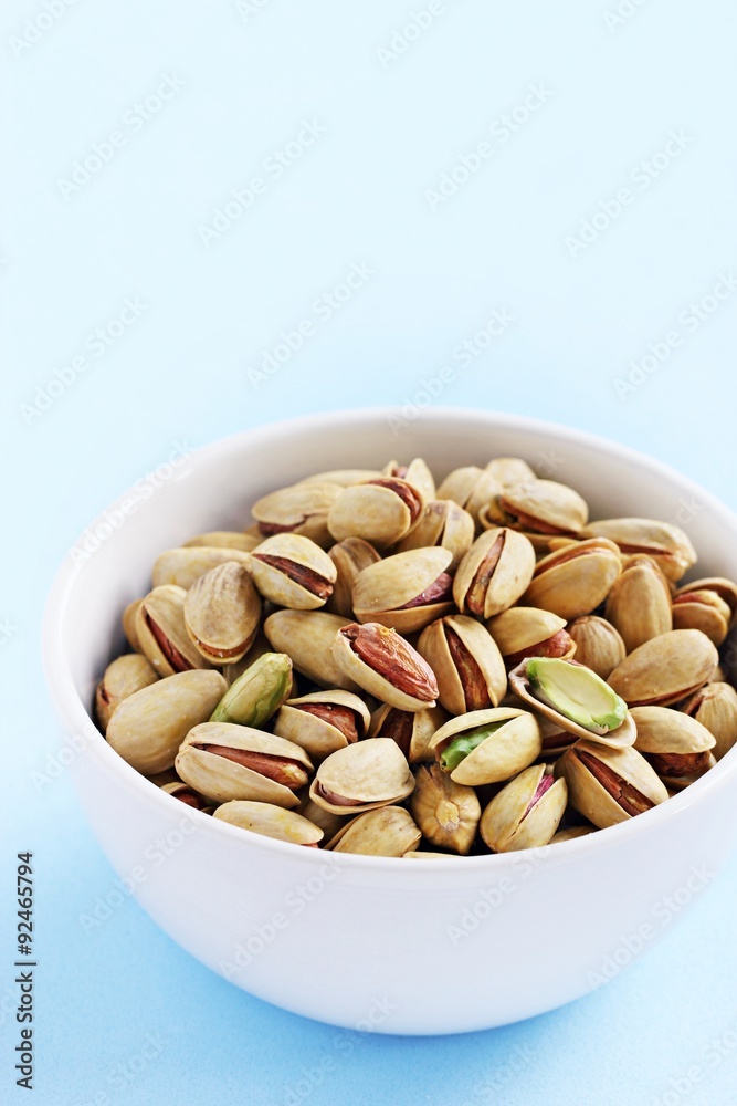 Pistachios nuts on a light blue background.Selective focus. Pistachios nuts on a light blue background.Selective focus.