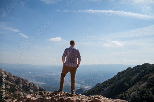 a man stands with his back to the top of the mountain