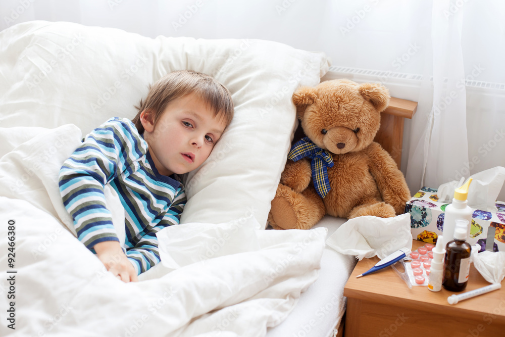 Sick child boy lying in bed with a fever, resting Sick child boy lying in bed with a fever, resting