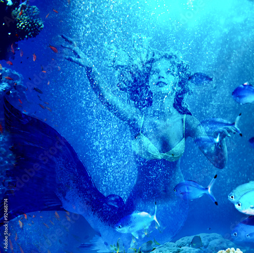 Tablou pe pânză Mermaid dive underwater through coral .