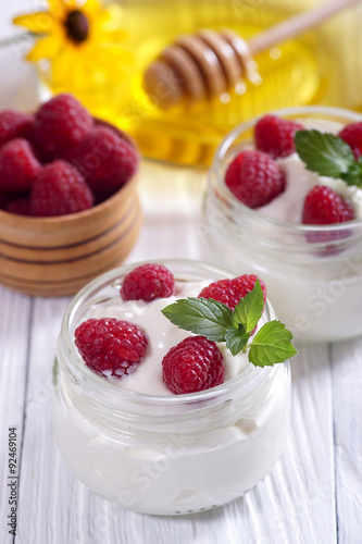 Yogurt with raspberries on a white table.