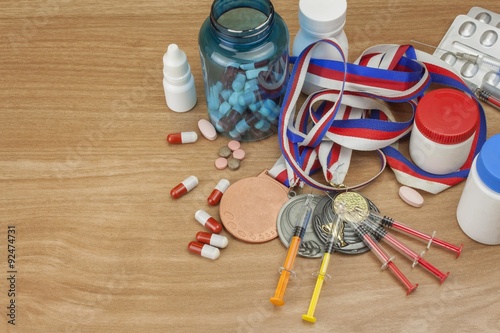 Doping in sport. Abuse of anabolic steroids for sports. Anabolic steroids spilled on a wooden table. Fraud in sports. Pharmaceutical industry. Sports fraud, fake winner.
 photo