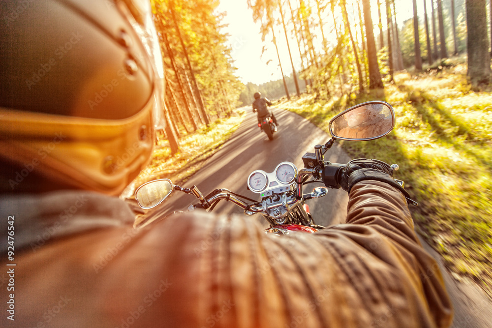 Naklejka premium Man seat on the motorcycle on the road in forest.