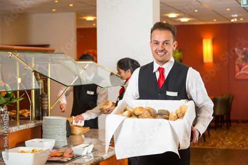 Waiter presenting bread basket at buffet in restaurant
