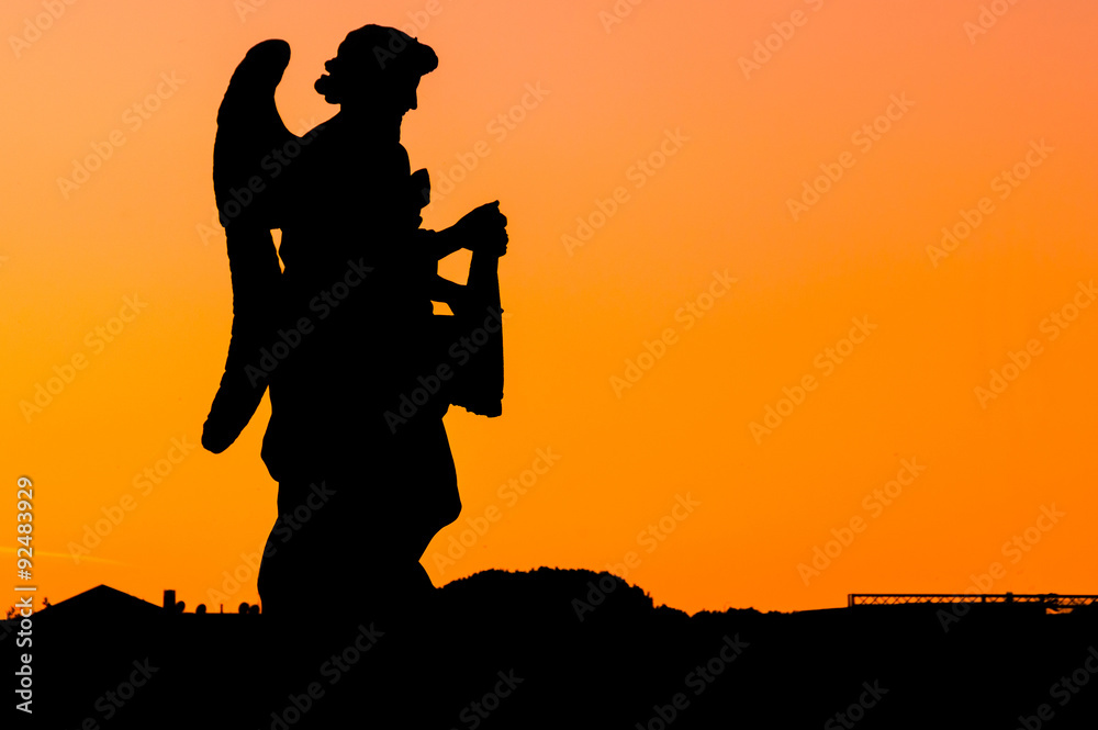 Sunset silhouette of an angel with the orange sky