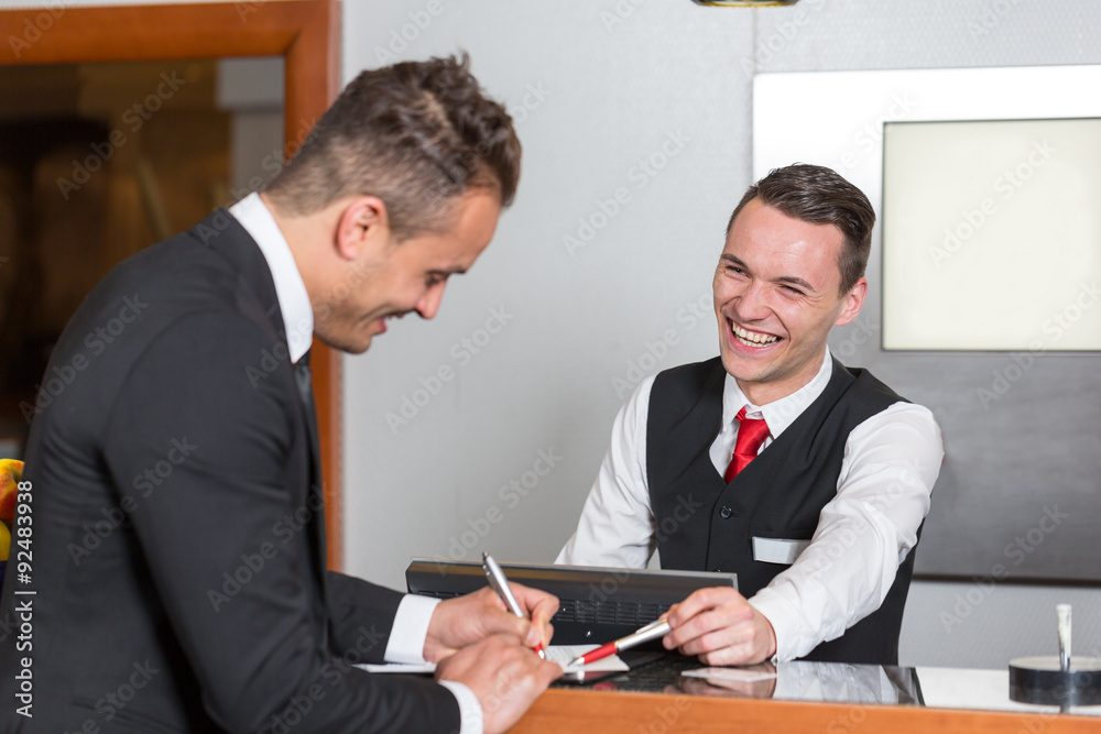 Receptionist at a hotel reception assisting guest Receptionist at a hotel reception assisting guest