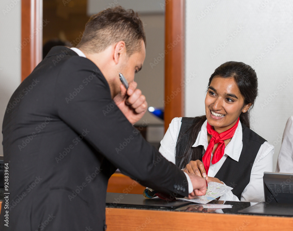 Receptionist at hotel reception assisting guest with city map Receptionist at hotel reception assisting guest with city map