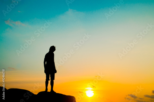 silhouette man stand on stone and sunset sky background