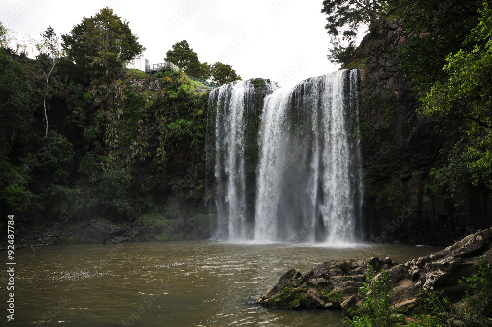 Fototapeta premium Whangarei falls from the river surface level on a cloudy day.