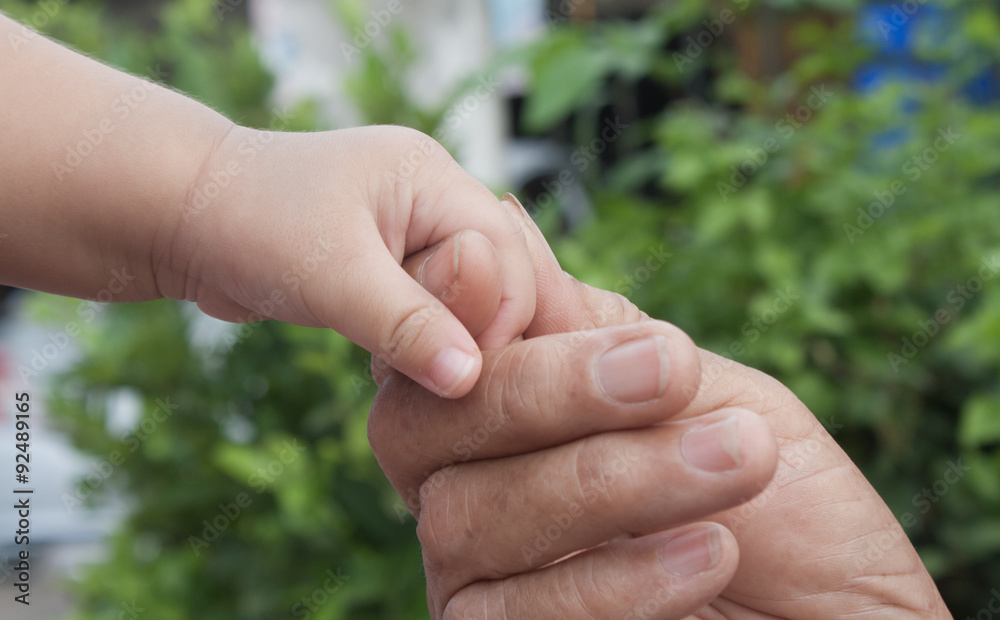 Baby's hand holding hands, old people, the engagement of the age difference. soft focus. Baby's hand holding hands, old people, the engagement of the age difference. soft focus.