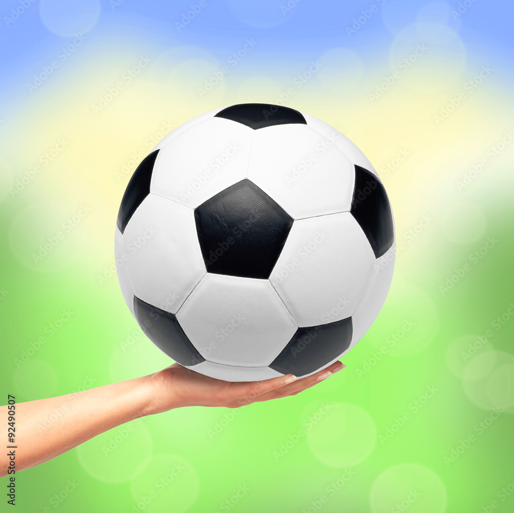 Fototapeta premium Hand holding soccer ball over bright nature background