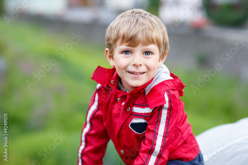 Portrait of little schoolboy outdoors on rainy day