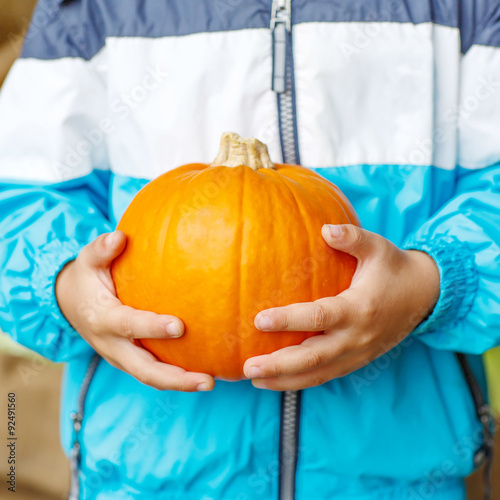 Hands of child holding pumpkin on harvest festival