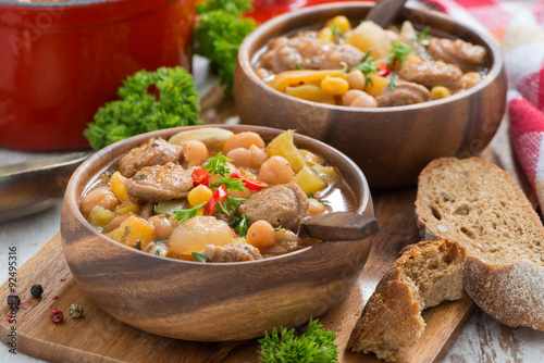 vegetable stew with sausages in a wooden bowl, close-up