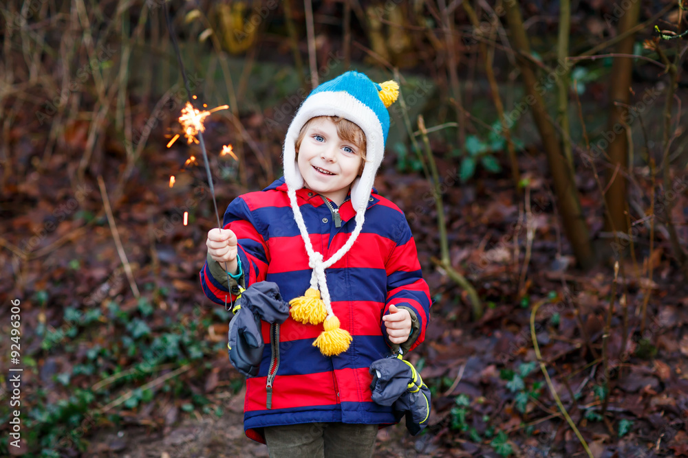 Little child in winter clothes holding burning sparkler Little child in winter clothes holding burning sparkler