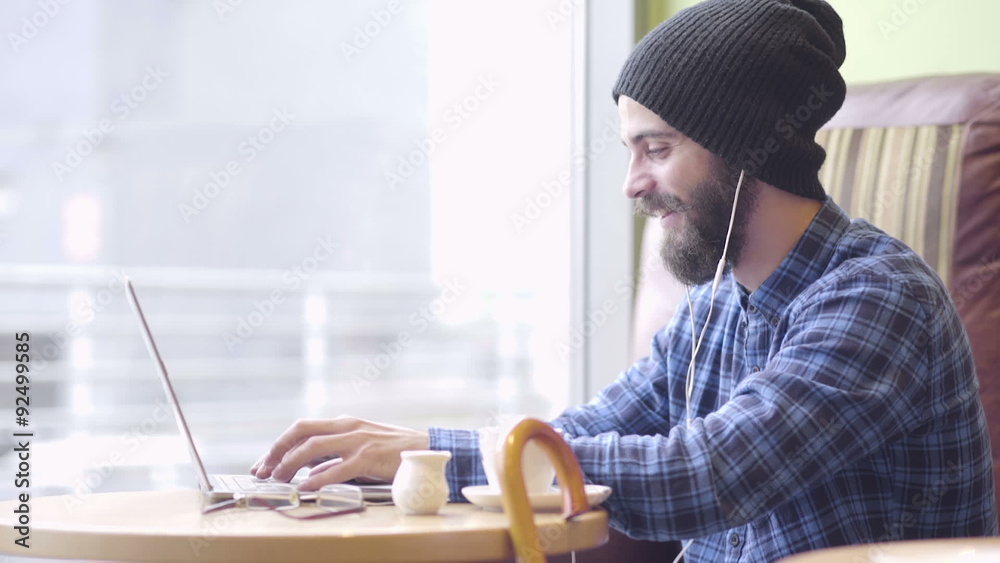 Young hipster fashion man working on laptop in coffee shop