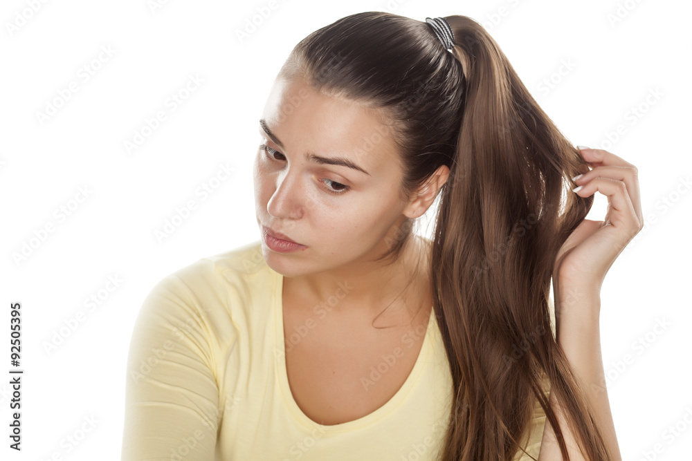 young woman without makeup touching her ponytail young woman without makeup touching her ponytail