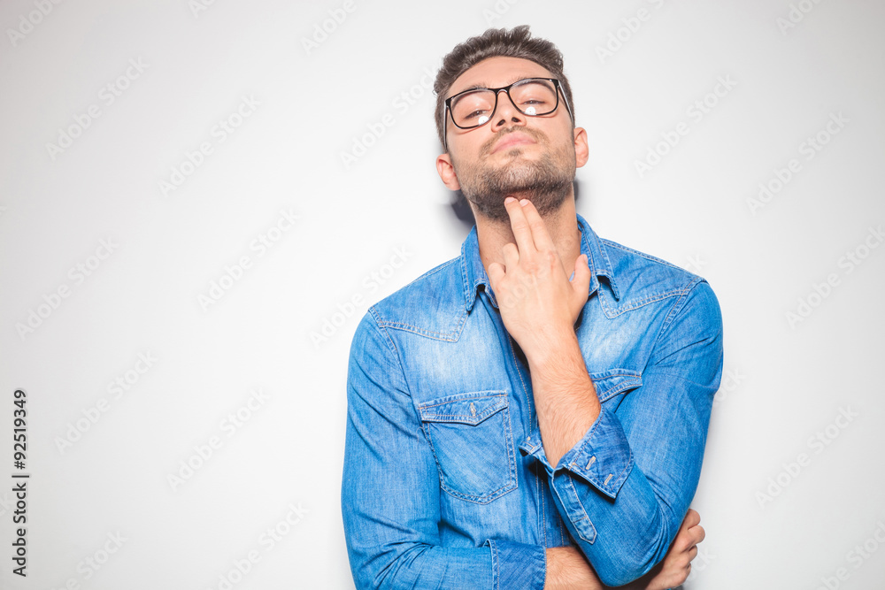 young man looking down at the camera while pointing to his chin young man looking down at the camera while pointing to his chin