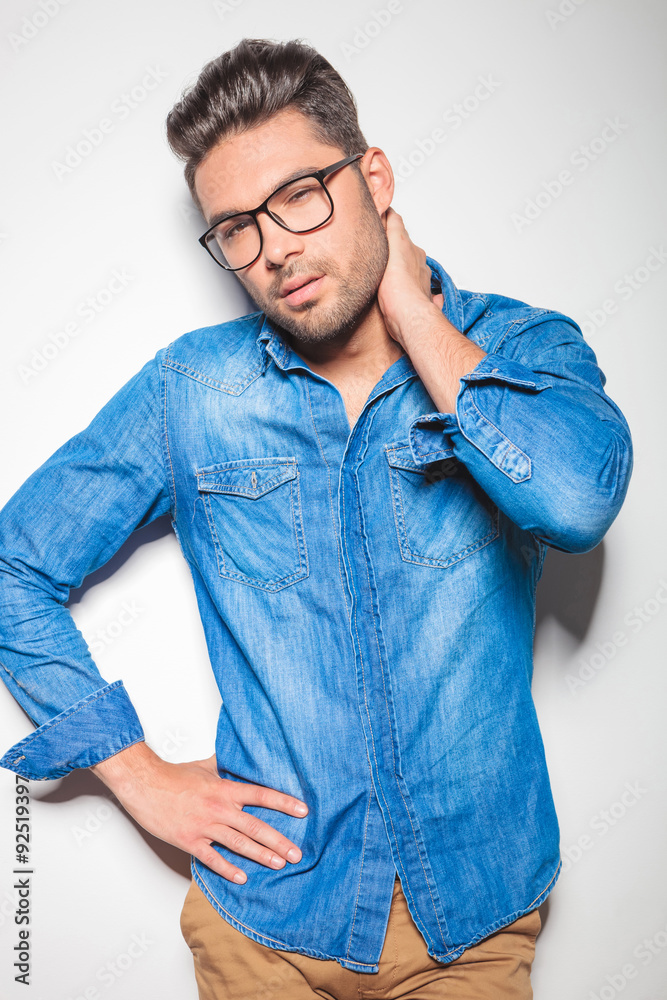 young beautiful man in denim touching his neck young beautiful man in denim touching his neck