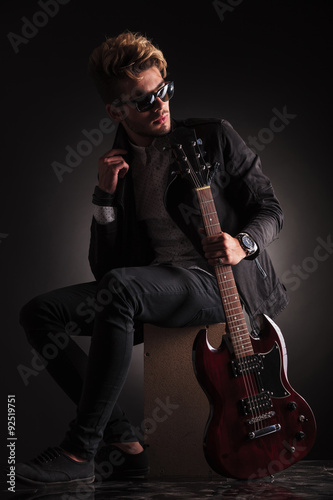 side view of a young guitarist sitting and looking back