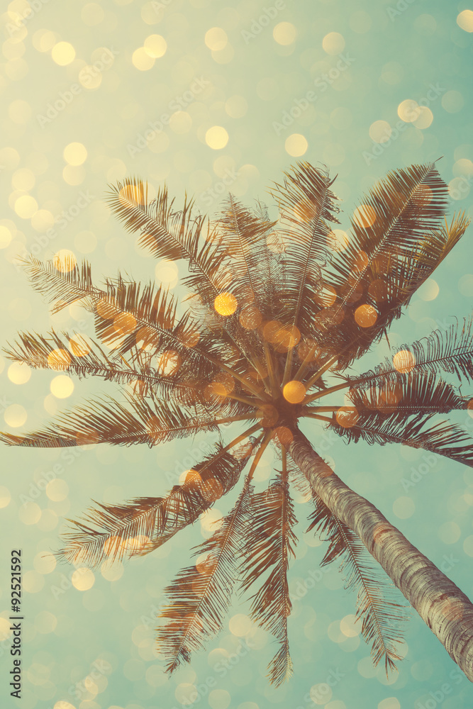 Fototapeta premium Vintage color stylized palm tree with bright party bokeh light overlay, double exposure effect