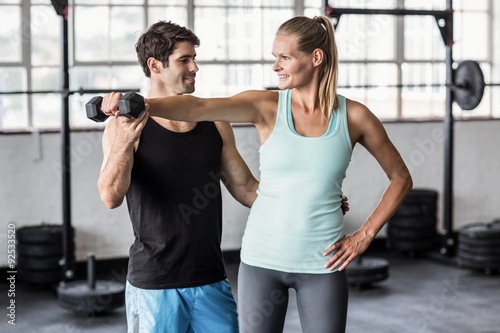  Male trainer helping woman with the dumbbells 