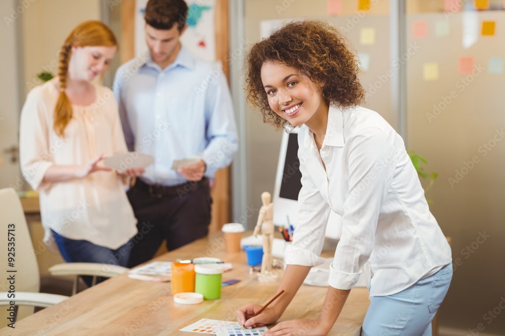 Businesswoman standing by table with colleagues Businesswoman standing by table with colleagues