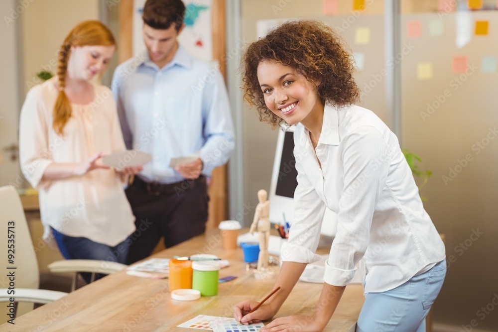 Businesswoman standing by table with colleagues 